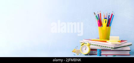 Beaucoup de différentes écoles, fournitures de bureau et de la papeterie. Concept de retour à l'école. Carnet, livre, stylo, crayon, ciseaux, réveil, horloge, autocollant sur une table en bois sur fond vert. Banque D'Images