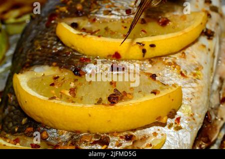 Macro photo d'un citron avec des épices sur le dessus du poisson dorado. Poisson espar doré recouvert de citrons. Banque D'Images