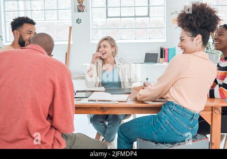 Groupe d'hommes d'affaires heureux et divers ayant une réunion dans un bureau moderne au travail. Des collègues joyeux rient et parlent tout en étant assis à une table Banque D'Images