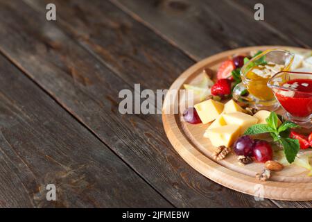 Fromage aux raisins et sauces sur l'espace d'imitation du bois Banque D'Images