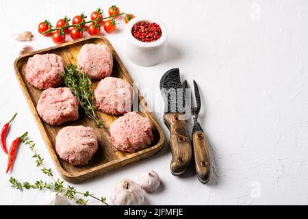 Des côtelettes de hamburgers crus de viande biologique, sur fond de table en pierre blanche, avec espace de copie pour le texte Banque D'Images
