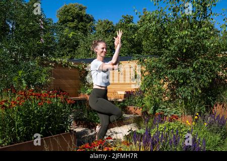 Londres, Royaume-Uni. 4 juillet 2022. Hannah Stevenson, instructeur de Pliates, effectue une routine de yoga dans le Lunch Break Garden, un jardin de mise en route, conçu par Inspired Earth Design, lors de la prévisualisation de la presse au RHS Hampton court Palace Garden Festival. Le plus grand spectacle floral au monde comprend des jardins de designers inspirants, des conférences de célébrités, des démonstrations et des ateliers. Credit: Stephen Chung / Alamy Live News Banque D'Images