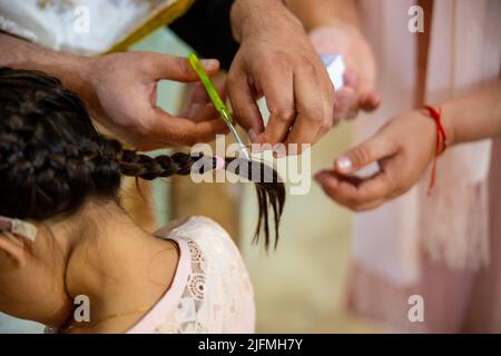 Un prêtre coupant les cheveux d'une petite fille pour sa cérémonie de baptême. Rituels du christianisme. Photo de haute qualité Banque D'Images