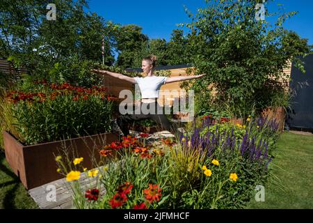 Londres, Royaume-Uni. 4 juillet 2022. Hannah Stevenson, instructeur de Pliates, effectue une routine de yoga dans le Lunch Break Garden, un jardin de mise en route, conçu par Inspired Earth Design, lors de la prévisualisation de la presse au RHS Hampton court Palace Garden Festival. Le plus grand spectacle floral au monde comprend des jardins de designers inspirants, des conférences de célébrités, des démonstrations et des ateliers. Credit: Stephen Chung / Alamy Live News Banque D'Images