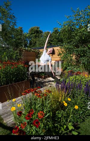 Londres, Royaume-Uni. 4 juillet 2022. Hannah Stevenson, instructeur de Pliates, effectue une routine de yoga dans le Lunch Break Garden, un jardin de mise en route, conçu par Inspired Earth Design, lors de la prévisualisation de la presse au RHS Hampton court Palace Garden Festival. Le plus grand spectacle floral au monde comprend des jardins de designers inspirants, des conférences de célébrités, des démonstrations et des ateliers. Credit: Stephen Chung / Alamy Live News Banque D'Images