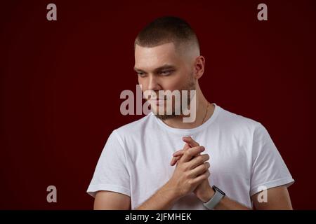beau homme dans un t-shirt blanc pense à quelque chose Banque D'Images