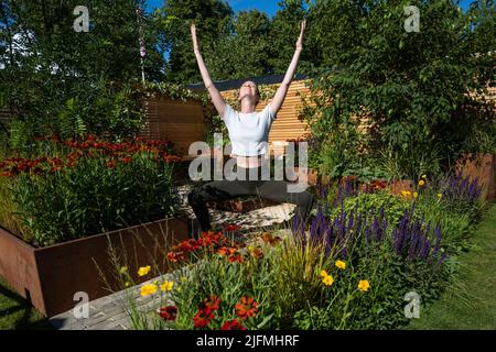 Londres, Royaume-Uni. 4 juillet 2022. Hannah Stevenson, instructeur de Pliates, effectue une routine de yoga dans le Lunch Break Garden, un jardin de mise en route, conçu par Inspired Earth Design, lors de la prévisualisation de la presse au RHS Hampton court Palace Garden Festival. Le plus grand spectacle floral au monde comprend des jardins de designers inspirants, des conférences de célébrités, des démonstrations et des ateliers. Credit: Stephen Chung / Alamy Live News Banque D'Images