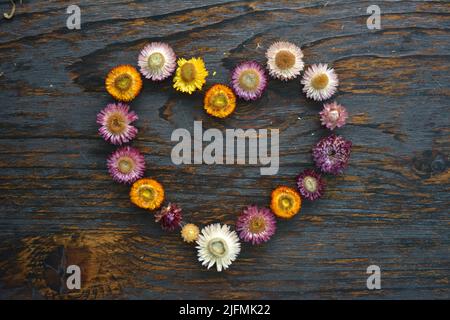 Beau coeur de fleurs sur fond de bois. Photo romantique pour anniversaire Banque D'Images