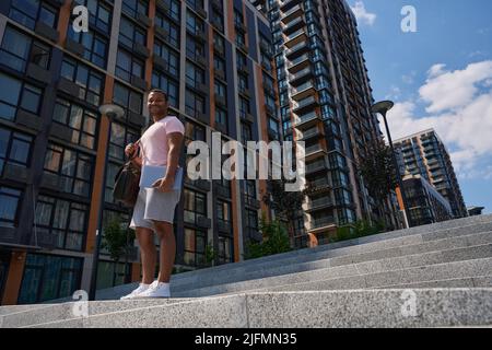 Un homme joyeux avec un ordinateur portable posé pour un appareil photo dans le quartier des affaires Banque D'Images