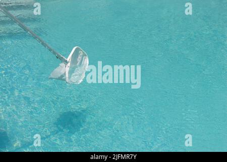 Dispositif de nettoyage de filet dans une piscine isolée sur l'eau avec l'espace de copie autour. L'activité de nettoyage de maison d'été pas de personnes Banque D'Images