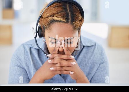Jeune femme de race mixte stressée agent de centre d'appels se faisant mal de tête en travaillant au bureau. Conseiller faisant des erreurs et de la difficulté avec Banque D'Images