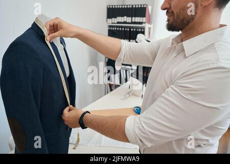 Homme couturier se tient avec du ruban adhésif pour mesurer la longueur Banque D'Images