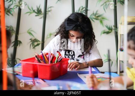 Petite fille colorant sur le papier à colorier et s'amusant à la table de classe d'art. Un enfant qui apprend à colorer à la maison ou à la maternelle. Banque D'Images