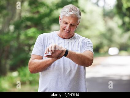 Permet de démarrer l'horloge et de l'utiliser. Photo d'un homme mature qui vérifie sa montre-bracelet tout en faisant de l'exercice à l'extérieur. Banque D'Images