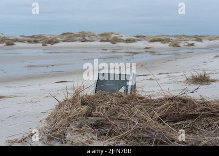 délavé tv crt / tube tv sur une plage, partiellement couvert de roseau et entouré de dunes de sable - à proximité avec l'espace vide Banque D'Images