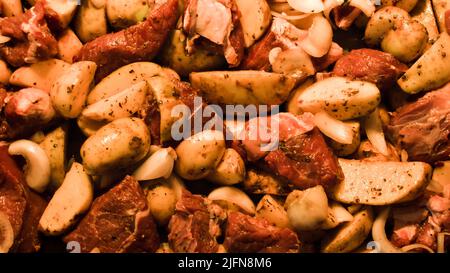 Faites-en une vue rapprochée de la viande crue avec des pommes de terre sur la plaque de cuisson avant de cuire épicée avec des herbes Banque D'Images