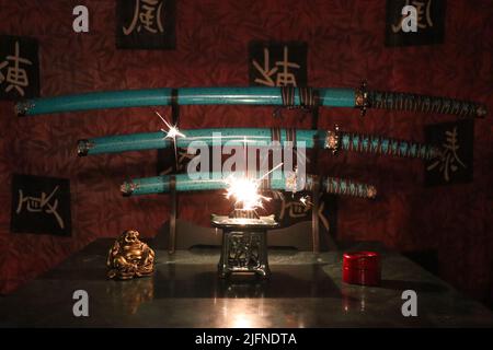 Une flamme devant les épées bleues samouraïs sur le stand dans une pièce avec des motifs japonais Banque D'Images