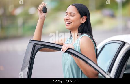 Une joyeuse femme de course mixte tenant les clés de sa nouvelle voiture. Une femme hispanique à la recherche heureuse d'acheter sa première voiture ou de réussir son test de conduite. Femme hispanique Banque D'Images