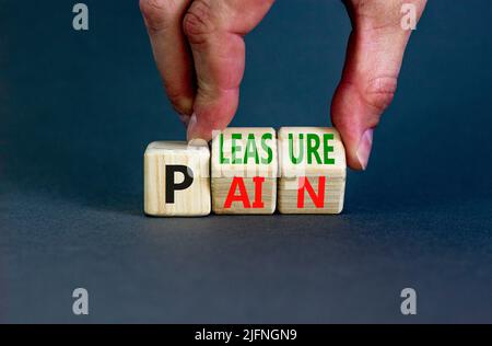 Symbole de douleur ou de plaisir. Concept mots douleur ou plaisir sur des cubes en bois. Main d'homme d'affaires. Magnifique fond gris de table. Les affaires et la douleur ou Banque D'Images