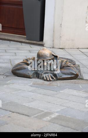 Statue en bronze excentrique (1997) d'un ouvrier d'égout (Čumil, l'observateur) émergeant d'un trou d'homme dans le centre de Bratislava, Slovaquie. Est-ce un tom pépirant ? Banque D'Images