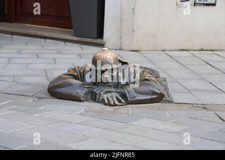 Statue en bronze excentrique (1997) d'un ouvrier d'égout (Čumil, l'observateur) émergeant d'un trou d'homme dans le centre de Bratislava, Slovaquie. Est-ce un tom pépirant ? Banque D'Images