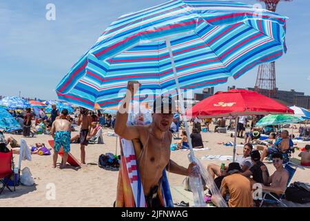 Coney Island, NY, États-Unis. 4th juillet 2022. La plage et la promenade de Coney Island regorgent de gens alors que New York célèbre le 4 juillet. Un vendeur de parasols sur la plage. Credit: Ed Lefkowicz/Alay Live News Banque D'Images