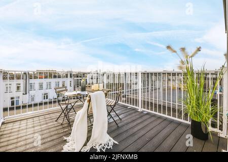 Une chaise avec une table et une vue panoramique depuis le toit d'un bâtiment de plusieurs étages sur la ville, le ciel avec des nuages Banque D'Images