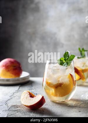 Limonade épicée de pêche d'été avec des tranches de menthe et de pêche sur fond texturé avec espace de texte Banque D'Images