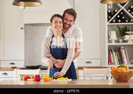 Ma belle femme est une grande cuisinière. Photo d'un homme qui embrasse sa femme pendant qu'elle prépare un repas dans la cuisine. Banque D'Images