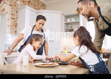 La pâtisserie est un amour rendu visible. Photo d'un couple et de leurs enfants qui cuisent ensemble à la maison. Banque D'Images