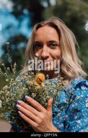 Belle fille tenant des fleurs sauvages et des canetons dans ses mains Banque D'Images