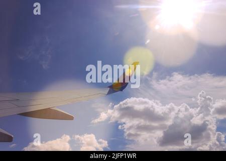 Vue sur une fenêtre de Southwest Airlines qui regarde les nuages, le ciel et les rayons du soleil Banque D'Images