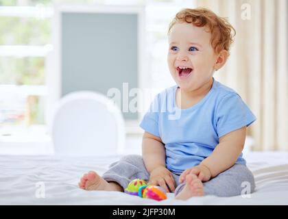 HES un lot de rires. Photo en longueur d'un adorable petit garçon jouant dans la chambre de ses parents à la maison. Banque D'Images