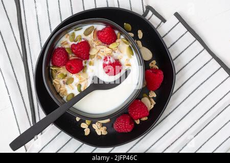 Vue en hauteur sur le yaourt à la vanille avec granola sans gluten et fruits dans un bol noir; espace pour les copies Banque D'Images