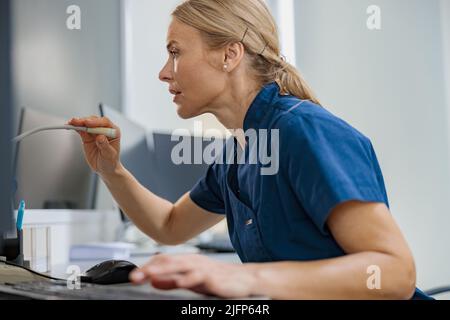 L'infirmière en service fait une annonce dans le microphone assis à la réception dans une clinique moderne Banque D'Images