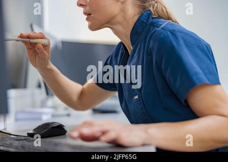 L'infirmière en service fait une annonce dans le microphone assis à la réception dans une clinique moderne Banque D'Images