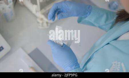 Le concept de traitement.action.Une jeune infirmière ouvre une nouvelle seringue et y insère une aiguille pour donner des injections et des vaccinations. Banque D'Images