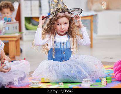 S'habiller est amusant. Photo d'une petite fille jouant de l'habillage en classe. Banque D'Images