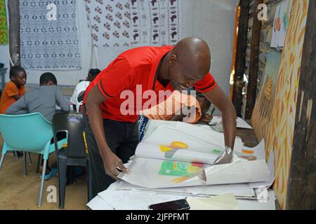 Windhoek, Namibie. 30th juin 2022. Frans Nambinga, artiste et fondateur de l'école d'art Frans Nambinga, aide les enfants à recueillir leurs peintures en classe à Windhoek, Namibie, 30 juin 2022. POUR ALLER AVEC "Feature: L'école d'art nourrit les rêves des enfants dans le village informel namibien" crédit: Ndalimfinga IITA/Xinhua/Alay Live News Banque D'Images