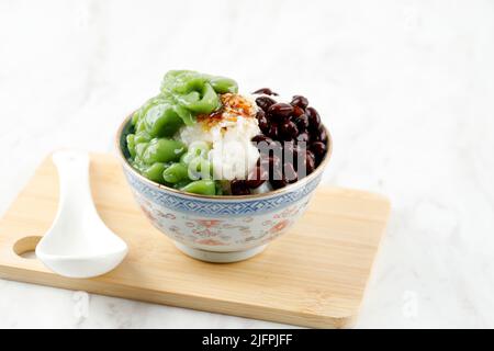 Desserts malaisiens appelés Cendol. Le Cendol est fait à partir de cubes de glace écrasés, de haricots rouges, de variété de sucreries et de fruits. Sur table blanche Banque D'Images