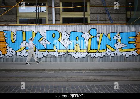 Lviv, Ukraine. 30th juin 2022. Une dame passe devant un mur avec des graffitis en Ukraine sur la place Rynok. Graffiti pour soutenir l'Ukraine et Azov. Crédit : SOPA Images Limited/Alamy Live News Banque D'Images