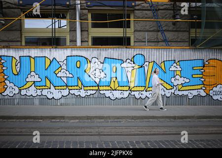 Lviv, Ukraine. 30th juin 2022. Une dame passe devant un mur avec des graffitis en Ukraine sur la place Rynok. Graffiti pour soutenir l'Ukraine et Azov. Crédit : SOPA Images Limited/Alamy Live News Banque D'Images