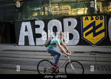 Lviv, Ukraine. 30th juin 2022. Un cycliste passe devant un mur avec des graffitis d'Azov sur la place Rynok. Graffiti pour soutenir l'Ukraine et Azov. Crédit : SOPA Images Limited/Alamy Live News Banque D'Images