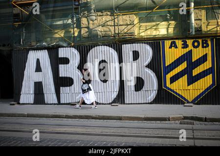 Lviv, Ukraine. 30th juin 2022. Une jeune femme passe devant un mur avec des graffitis Azov sur la place Rynok. Graffiti pour soutenir l'Ukraine et Azov. Crédit : SOPA Images Limited/Alamy Live News Banque D'Images