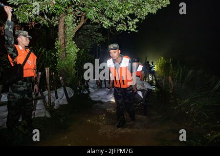BEIHAI, CHINE - le 4 JUILLET 2022 - des policiers et des soldats armés utilisent des sacs de sable, des piquets et des planches de bois pour construire un barrage pour bloquer la brèche à Beihai Banque D'Images