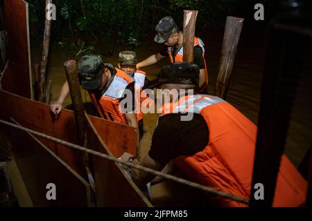 BEIHAI, CHINE - le 4 JUILLET 2022 - des policiers et des soldats armés utilisent des sacs de sable, des piquets et des planches de bois pour construire un barrage pour bloquer la brèche à Beihai Banque D'Images