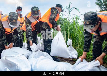 BEIHAI, CHINE - le 4 JUILLET 2022 - des policiers et des soldats armés utilisent des sacs de sable, des piquets et des planches de bois pour construire un barrage pour bloquer la brèche à Beihai Banque D'Images