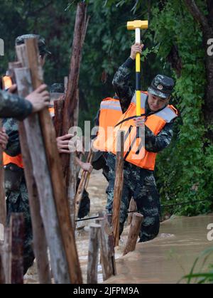 BEIHAI, CHINE - le 4 JUILLET 2022 - des policiers et des soldats armés utilisent des sacs de sable, des piquets et des planches de bois pour construire un barrage pour bloquer la brèche à Beihai Banque D'Images