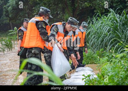 BEIHAI, CHINE - le 4 JUILLET 2022 - des policiers et des soldats armés utilisent des sacs de sable, des piquets et des planches de bois pour construire un barrage pour bloquer la brèche à Beihai Banque D'Images