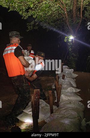 BEIHAI, CHINE - le 4 JUILLET 2022 - des policiers et des soldats armés utilisent des sacs de sable, des piquets et des planches de bois pour construire un barrage pour bloquer la brèche à Beihai Banque D'Images